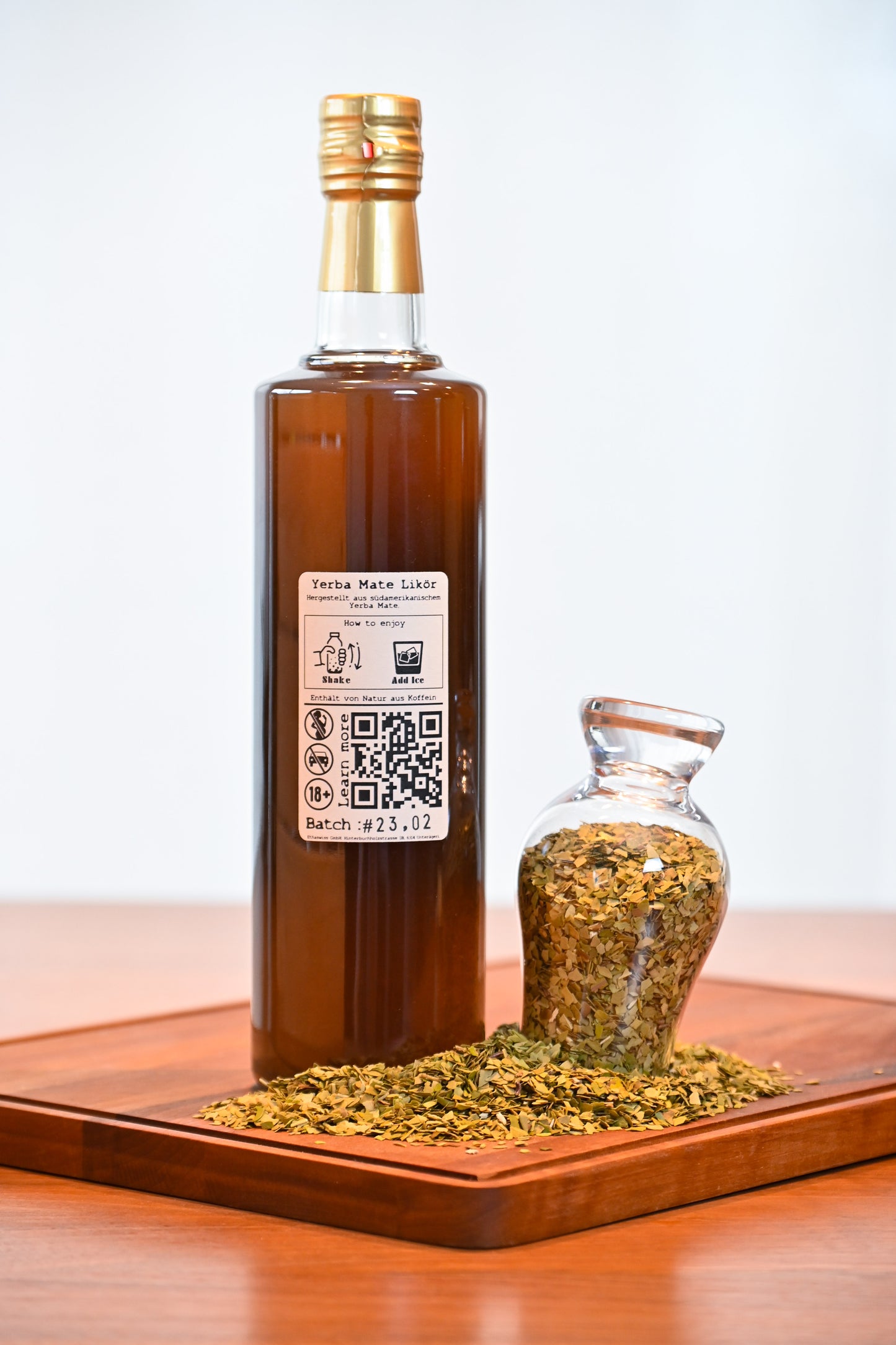 THE MATE bottle 700ml standing on a wooden cupboard with some yerba mate next to it